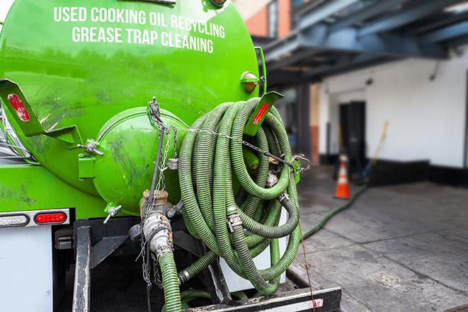 a technician pumping a grease trap in a commercial building in Woodside